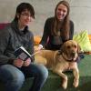 Studentin Anna Tegler und ihr Labrador Ginger lauschen Schüler Emanuel beim Vorlesen. 	