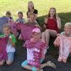 Die Kinder freuen sich über ihre gelungenen Batik-T-Shirts. Hinten im Bild die Betreuerinnen Marlene Geiselmann (links) und Aurelia Koch. 	 	