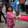 Eine Frau gibt einem Flüchtlingskind ein paar Münzen als kleine Gabe.