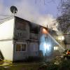 Feuerwehrleute stehen bei Löscharbeiten vor den verqualmten und teils brennenden Container-Einheiten einer Flüchtlingsunterkunft in Hamburg-Winterhude.