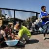 Ein Bild aus Santiago de Chile vom 28. Februar. Eine Familie badet auf offener Straße ihr Baby, ein junger Mann trägt einen Wasserkanister vorbei.