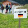 Flüchtlinge gehen nahe der deutschen Grenze hinter einem Schild mit der Aufschrift «Germany».