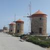 Der Hafen von Mandraki in Rhodos-Stadt bietet eine wunderschöne Fotokulisse. Der Steg zur Festung Agios Nikolaos führt entlang von Windmühlen (rechts) und teuren Luxusjachten (links).