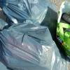 Eine zunächst Unbekannte entsorgt illegal Müll nahe der Altglascontainer in Wemding. Die Polizei ermittelt die Täterin.