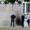Polizisten untersuchen den schwarzen Fleck an der Fassade der Synagoge, der durch Brandanschlag entstanden ist.