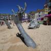 13.06.2021, Großbritannien, St Ives: Eine Skulptur des Künstlers Ruscoe, die einen ertrinkenden Mann darstellt inmitten der Strandgänger während des G7-Gipfels. Der G7-Gipfel findet vom 11. bis 13. Juni in Carbis Bay, St Ives in Cornwall statt. Foto: Jon Super/AP/dpa +++ dpa-Bildfunk +++