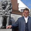 Bürgermeister Josef Schmidberger am Brunnen im Zentrum Holzheims neben einem Löwen. Das Tier ist zufällig auch sein Sternzeichen. 	 	