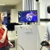 Ahmad Alili (rechts) taucht mit VR-Brille und Controller ins menschliche Herz ein, der Bildschirm im Hintergrund zeigt, was der Medizinstudent gerade sieht. Tutorin Eva Enghofer erklärt das Programm, Kommilitone Marin Zaimi (im Hintergrund) sieht interessiert zu. 