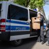 Polizeibeamte entladen einen Transporter mit sichergestelltem Material aus einer Razzia.