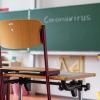 «Coronavirus» steht auf einer Tafel in einem leeren Klassenzimmer. Im Landkreis Landsberg haben sich mehrere Schüler infiziert.