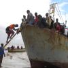 Ein Boot mit etwa 100 Menschen, die aus der überfluteten Region Buzi gerettet wurden, legt an einem Strand an.