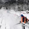 Helfer befreien die Zuschauertribünen in Ruhpolding vom Schnee.  	