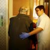 Eine Mitarbeiterin eines ambulanten Pflegediensts hilft einem Rentner in dessen Wohnung. 