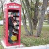Volker Sieg sortiert den kleinen Bücherschrank in der ausgedienten Telefonzelle auf dem Dorfplatz in Straß. 