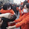 Ihr Einsatz ist beendet: Mitarbeiter mit Mundschutzmasken aus Ostchina (in Orange) verabschieden sich in Wuhan von Mitarbeitern aus der nordwestchinesischen Provinz Qinghai. Sie arbeiteten gemeinsam im selben provisorischen Krankenhaus für Corona-Patienten. Doch dort gibt es aktuell keine Neuinfektionen mehr. 	