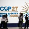 Teilnehmerinnen und Teilnehmer der Weltklimakonferenz in Scharm el Scheich vor dem Logo der COP27.