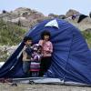 Drei Flüchtlingskinder stehen vor einem Zelt im Dorf Petra auf der nordöstlichen Ägäisinsel Lesbos.  