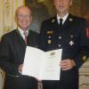 Kreisbrandinspektor Klaus Hartwig bekommt das Steckkreuz des Feuerwehrehrenzeichens mitsamt Urkunde überreicht. 	