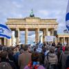 Teilnehmer der Kundgebung „Aufstehen gegen Terror, Hass und Antisemitismus – in Solidarität und Mitgefühl mit Israel“ vor dem Brandenburger Tor schwenken israelische Flaggen.