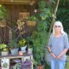 Karin Gagelmann an der mit Brombeeren bepflanzten und liebevoll dekorierten Gartenhütte am Waldrand. 