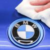 Ein BMW-Mitarbeiter poliert das Logo eines BMW mit einem Tuch.