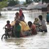 Bewohner eines Ortes in Indien  waten durch das Hochwasser. 