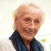 Die 105-jährige Christina Feindel sitzt lachend in ihrem Zimmer in einem Pflegeheim. Sie ist eine der letzten Zeitzeugen, welche die Revolution in Bayern 1918 miterlebten.