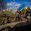 Ukrainische Soldaten halten eine ukrainische Fahne, während sie auf einem gepanzerten Fahrzeug eine Straße zwischen Isjum und Lyman entlang fahren.