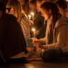 Gläubige sitzen bei einem Gebet mit brennenden Kerzen in der Donauarena in Regensburg.