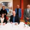 Geschäftsführerin des Freizeitparks Manuela Stone und Schulleiter Oliver Wahl (vorne) unterzeichnen die Partnerschaftsurkunden.