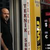Ein Ladenbesitzer steht neben einer Anzeigetafel, die die Wechselkurse der türkischen Lira anzeigt.