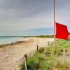 In Palma De Mallorca weht eine rote Flagge auf Halbmast über dem leeren Strand Ses Covetes. In Folge des Coronavirus' ist unklar, wann Urlauber aus dem Ausland wieder kommen dürfen.
