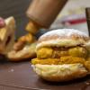 Bäckermeister Florian Perkmann bereitet einen Wurst-Krapfen in seiner Bäckerei zu.