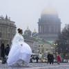 Eine Braut geht über den Schlossplatz in St. Petersburg. In Russland finden derzeit viele Trauungen statt, damit Paare zumindest ein Recht auf Informationen haben, sollte der Partner im Krieg verletzt werden. 