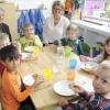 Kindergartenleiterin Anne-Rose  (links) und Ernährungsexpertin Claudia Wiedemann mit Kindern der Kita St. Laurentius.  	