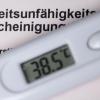 Ein Fieberthermometer liegt auf einer Arbeitsunfähigkeitsbescheinigung.