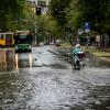 Eine Person fährt mit einem Motorroller eine überschwemmte Straße entlang.