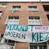 Ein Transparent gegen Investoren und Gentrifizierung hängt an der Fassade eines Hauses in Berlin-Neukölln.
