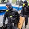 Polizisten tragen bei einer Hausdurchsuchung in Berlin-Kreuzberg einen Karton zu einem Fahrzeug.