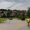 Ein Auto steckt nahe Memmelsdorf Oberfranken) auf einer überfluteten Landstraße fest.
