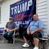Dave Mitchko (rechts), hier mit seinem Freund John Foley, hat seine Garage zum Lager für Trump-Werbematerial umgebaut. Handy und Pistole liegen neben ihm auf der Bank. 
