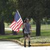 Ein Mann joggt mit einer Nationalflagge der Vereinigten Staaten eine Straße in Houston (Texas) entlang.
