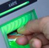 Eine Bankkundin steckt ihre Girocard in einen Geldautomaten.