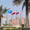 Flaggen in den Farben Katars und eine Fifa-Flagge sind hinter Palmen zu sehen.