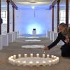 Cornelia Rapp entzündet einen Kerzenring in ihrer Installation „Mut“ in einem ehemaligen Stall. 	 	
