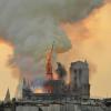 Flammen und Rauch schlagen aus der Kathedrale Notre Dame auf, der kleine Spitzturm (Mitte) beginnt einzustürzen.