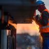 Ein Arbeiter führt auf einer Baustelle Schweißarbeiten an einer Brücke aus.