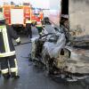 Feuerwehrleute stehen am Samstag (10.12.11) auf der Autobahn 3 (A3) nahe Limburg neben einem ausgebrannten Pkw, der unter einen Lkw-Auflieger gerast war.