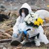 Eine Frau betet und legt Blumen nieder an der Stelle an der ihr Haus stand, das durch den Tsunami, der auch das nahegelegene Kernkraftwerk Fukushima beschädigt hat, zerstört wurde. 