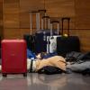 Reisende liegen am Flughafen BER am frühen Morgen auf dem Boden und schlafen.